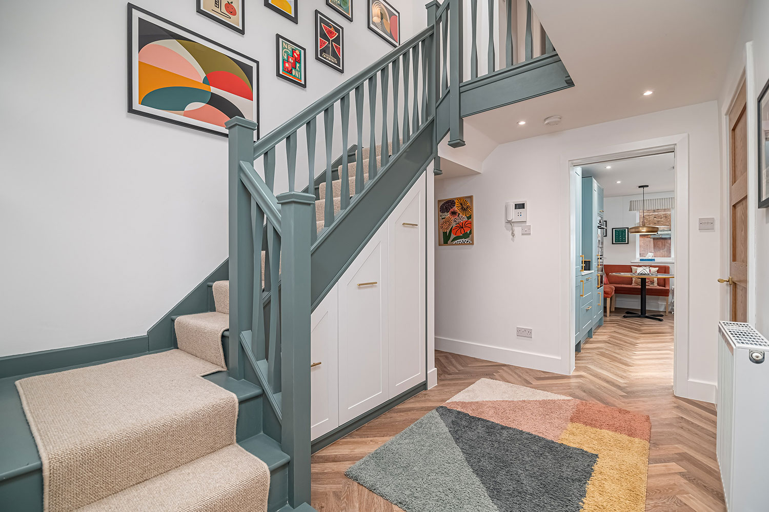 Entrance hall interior design, teal staircase, colourful art