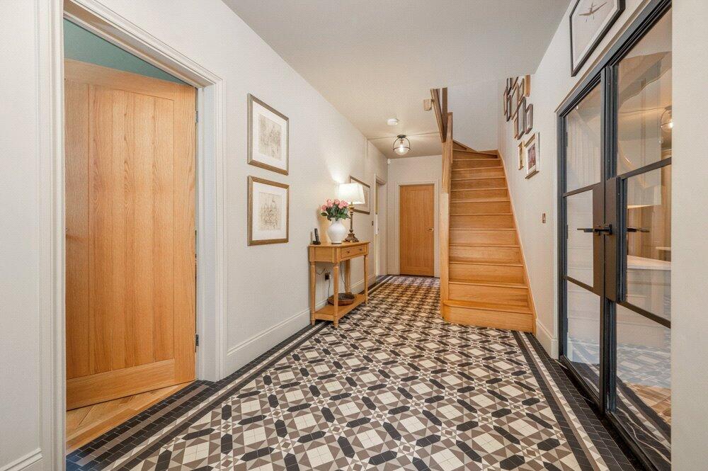 Large hallway with moziac tiles and wooden staircase